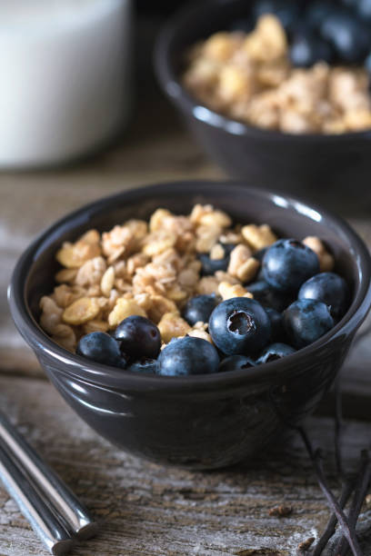 istock Granola with fresh blueberries in black bowl on a rustic old wooden table. 669670696