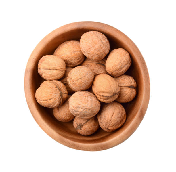 istock Walnuts in wooden plate isolated on white 669673850