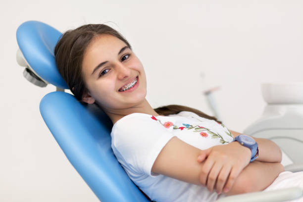 милая девочка-подросток улыбается с ее скобки в кабинете стоматолога - dentist teenager dental hygiene sitting стоковые фото и изображения