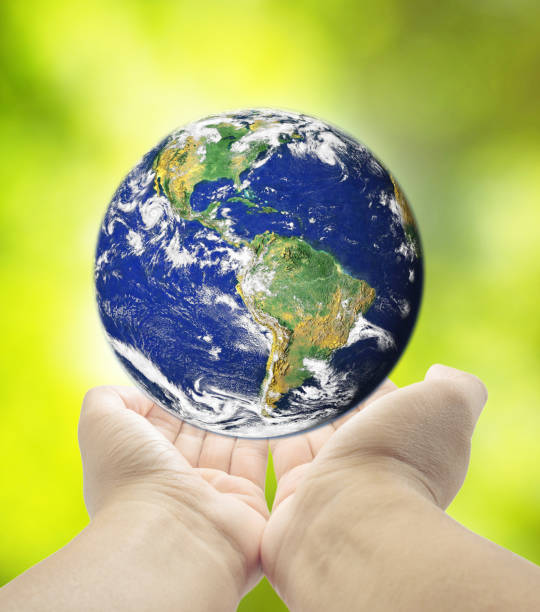 istock holding planet Earth in hands against  green grass spring background 669688930