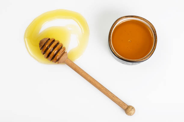 istock Freshly fragrant honey into a bowl and dipper on white backgroun 669694958