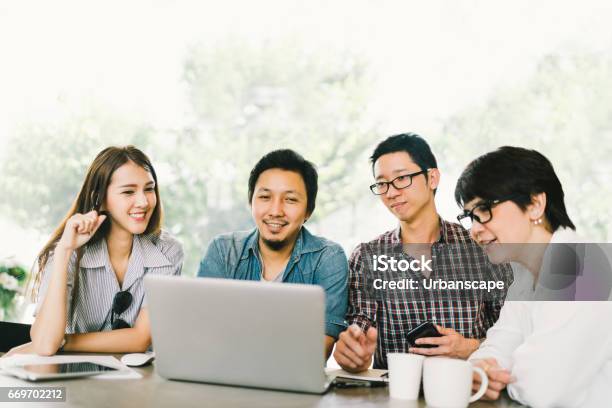 Diverse Group Of Asian Business Coworkers Or College Students Using Laptop In Team Casual Meeting Startup Project Discussion Or Happy Teamwork Brainstorm Concept At Coffee Shop Or Modern Office Stock Photo - Download Image Now