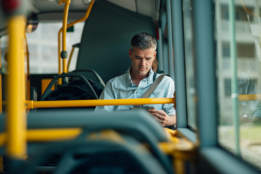 Confident businessman traveling by bus and using a digital tablet