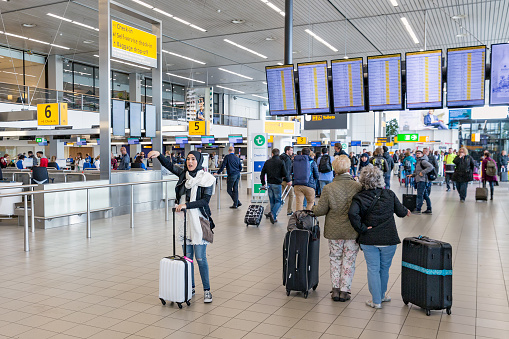 AMSTERDAM, THE NETHERLANDS - MAY 16, 2016: Travellers and waving woman with headscarf at Schiphol Airport near Amsterdam in The Netherlands