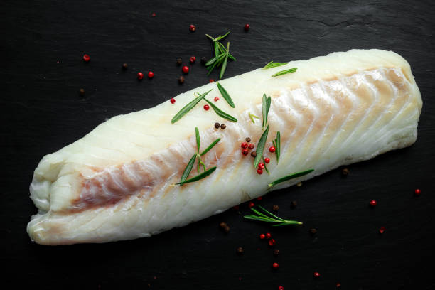 istock Fresh Raw Cod loin fillet with rosemary, cracked pepper on stone board 669709158