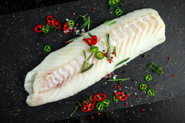 istock Fresh Raw Cod loin fillet with rosemary, chillies, cracked pepper on stone board 669709380