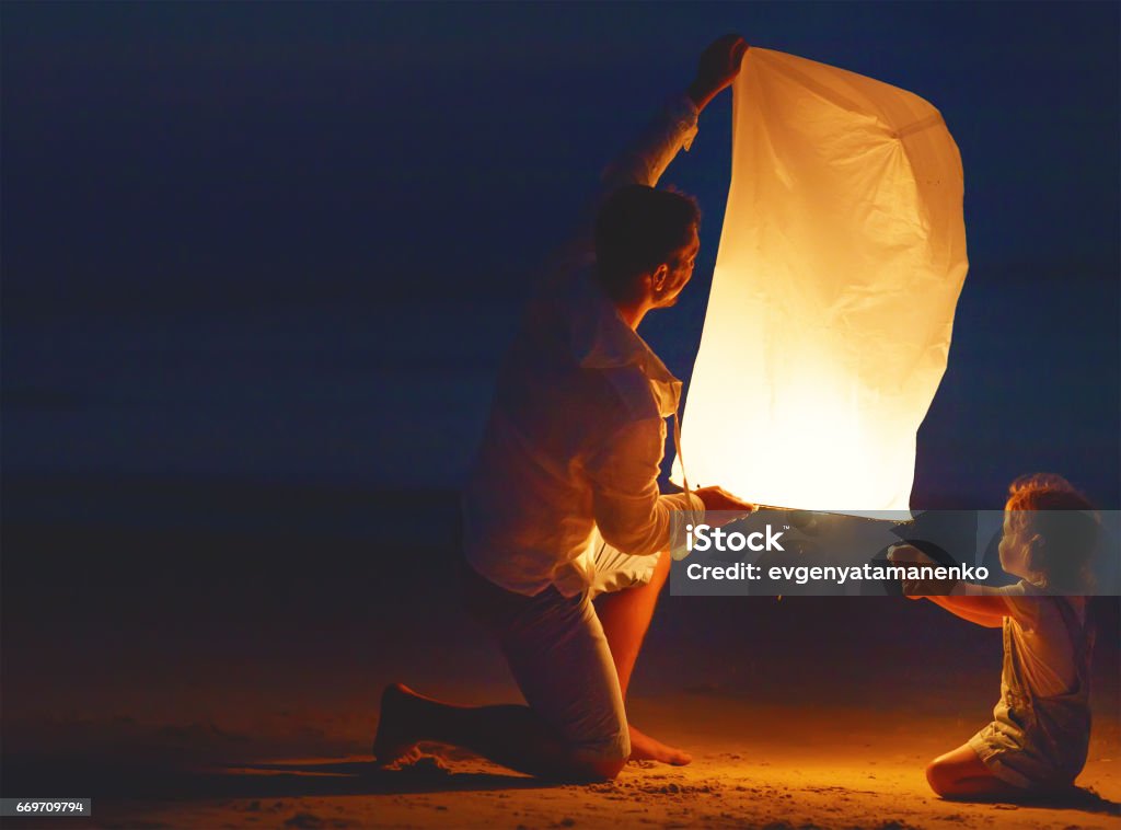 Família enviar lâmpada de lanterna celestial de ar em voo na praia - Foto de stock de Lanterna royalty-free