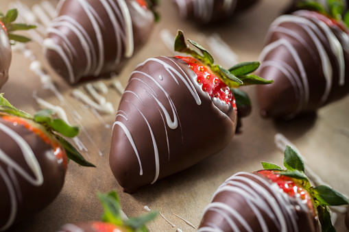 Chocolate covered strawberries with milk chocolate and white chocolate on parchment paper.