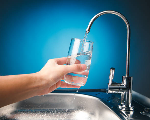 hand pouring a glass of water from filter tap - transparent holding glass focus on foreground imagens e fotografias de stock