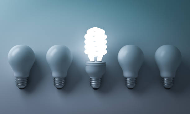 istock Energy saving light bulb , one glowing compact fluorescent lightbulb standing out from unlit incandescent bulbs on cyan background , individuality and different creative idea concepts . 3D rendering 669719408