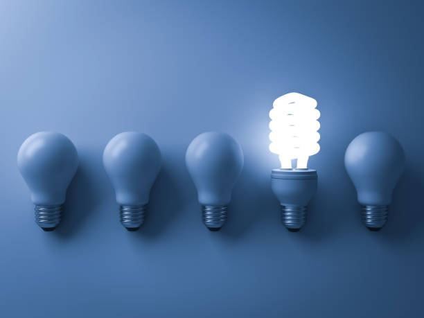 istock Energy saving light bulb , one glowing compact fluorescent lightbulb standing out from unlit incandescent bulbs on blue background , individuality and different creative idea concepts . 3D rendering 669719564