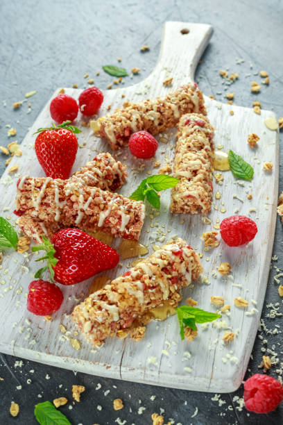 istock Granola bar with strawberries, raspberry honey and white chocolate on cutting board 669722640