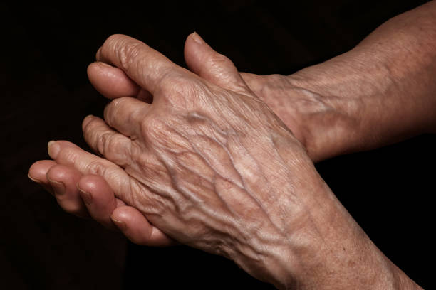 Folded senior woman wrinkled hands close up. Old age, age problems, poverty and loneliness theme Folded senior woman wrinkled hands close up. On abstract background, clipping path included. Old age, age problems, poverty and loneliness theme 70s theme stock pictures, royalty-free photos & images