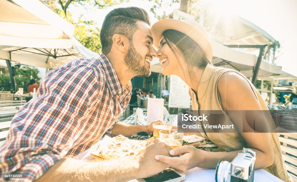 Couple in love kissing at bar eating local delicacie on travel excursion - Young happy tourists enjoying moment at street food restaurant - Relationship concept with lovers at first date - Warm filter Table For Two Stock Photo