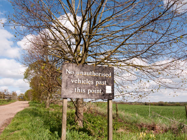 A Sign that Says No Unauthorised Vehicles Past this Poing in the Countryside on a sunny day, Wooden Sign with old Font and Type, No Cars, No People, Private, Special, Parking, Personal, Farmland, Fenced un letrero que no dice ningún vehículo no autorizado pasado este poing en campo en un día soleado, cartel de madera con la antigua fuente y tipo, no coches, no personas, privado, especial, estacionamiento, personal, las tierras de labrantío, alambrado