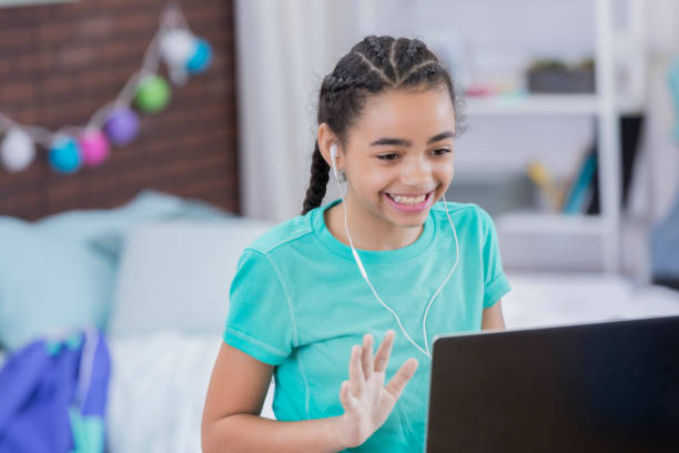 istock Preteen girl waves while video chatting 669745054