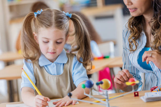 istock Little girl concentrates on assignment at school 669745212
