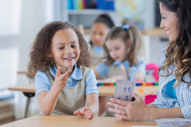 istock Little girl counts on fingers while using flashcards 669745218