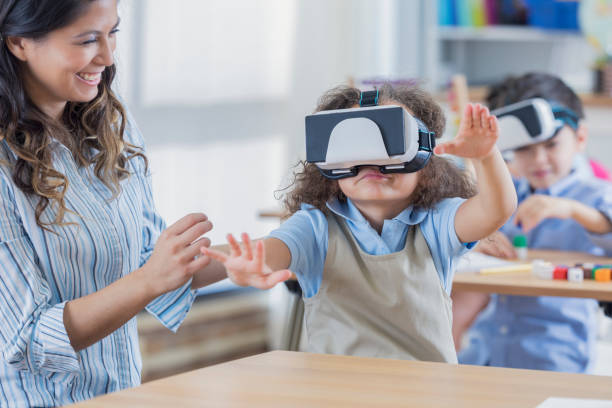 istock Little girl uses virtual reality goggles at school 669745224