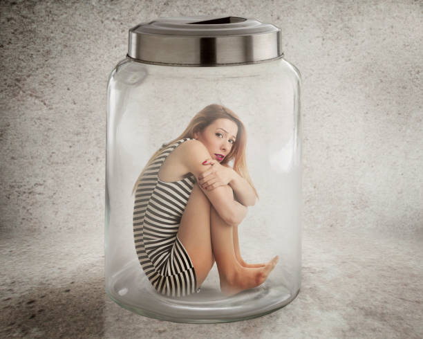 istock Young lonely woman sitting in glass jar 669765400