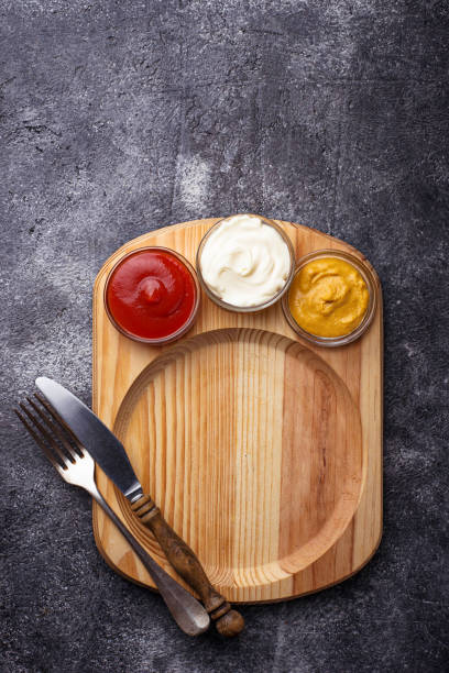 istock Food background with mustard, ketchup, mayonnaise, fork and knife. 669772442