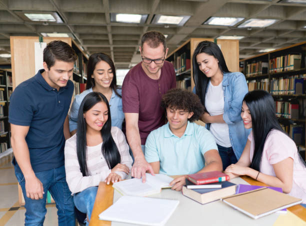 istock Teacher with a group of students at a library 669775624
