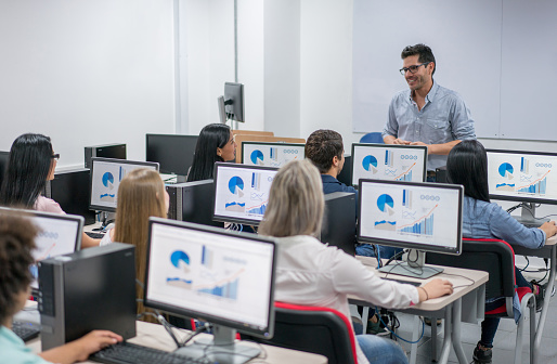 Profesor dando una clase de informática en la escuela a un grupo de estudiantes photo