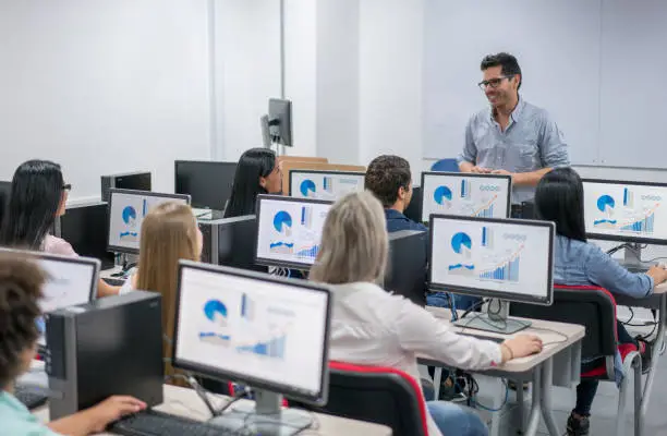 Photo of Teacher giving an IT class at school to a group of students