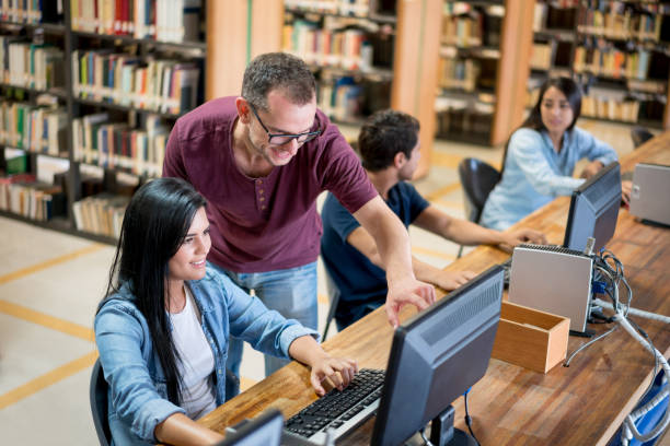 profesor ayudar a los estudiantes en la biblioteca - professor librarian university library fotografías e imágenes de stock