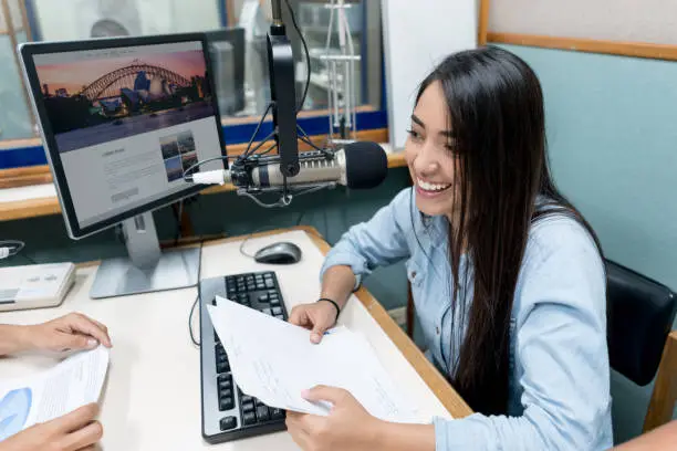 Happy Latin American female student broadcasting from the university's radio station - education concepts. Image on screen belongs to AndresR, interface was made from scratch by us.