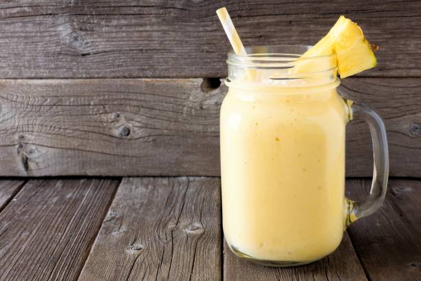 istock Pineapple smoothie in a mason jar against wood 669779442