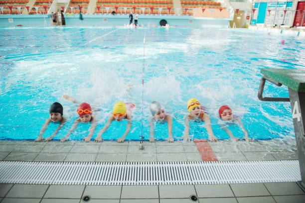 istock happy children kids group at swimming pool class learning to swim 669784932