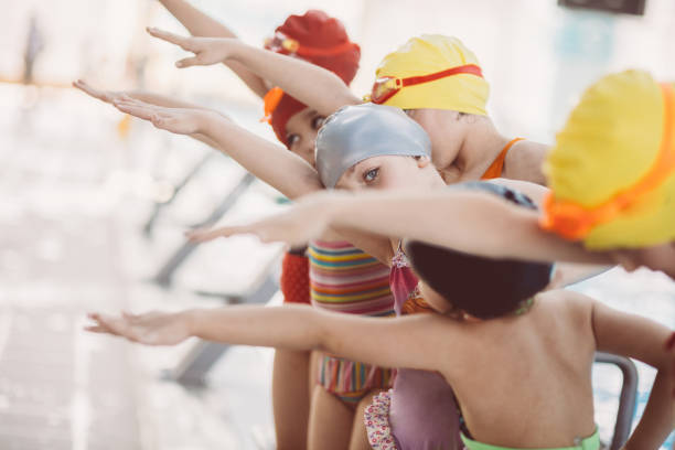 instructor and group of children doing exercises near a swimming pool - blue water swimming pool sports and fitness imagens e fotografias de stock