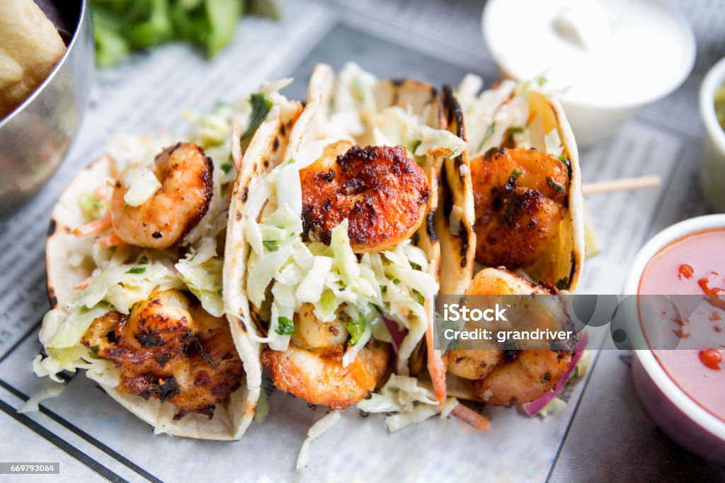 Grilled Shrimp Tacos Grilled jumbo shrimp in corn tortilla tacos with cabbage garnish on an old fashioned newspaper wrapper. Taco Stock Photo