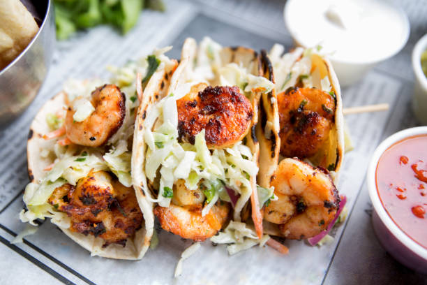 Grilled Shrimp Tacos Grilled jumbo shrimp in corn tortilla tacos with cabbage garnish on an old fashioned newspaper wrapper. ready to eat photos stock pictures, royalty-free photos & images