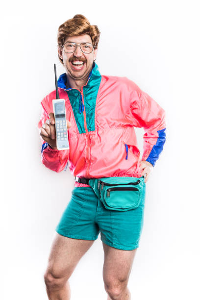 Nineties Tech and Fashion Style Man A man wearing fluorescent colored clothing and a fanny pack holds up a 1980's - 1990's cellular brick phone, representing state of the art style and technology for that time. bizarre fashion stock pictures, royalty-free photos & images