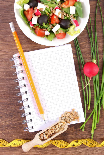 istock Fresh greek salad with vegetables, centimeter and notepad for writing notes, healthy nutrition and slimming concept 669835404