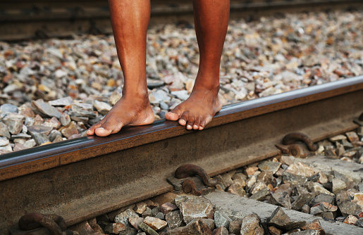 Barefoot young man walking on train track with making balancing.