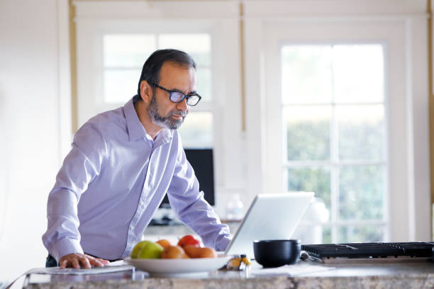 istock Hispanic Businessman Working From Home Stands At His Kitchen Counter 669839400