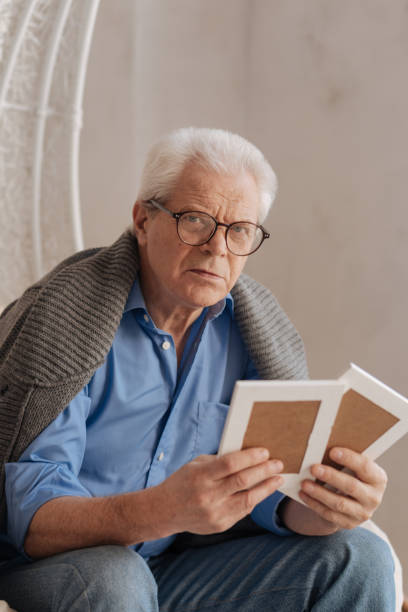 istock Gloomy unhappy man having old photos in his hands 669843566