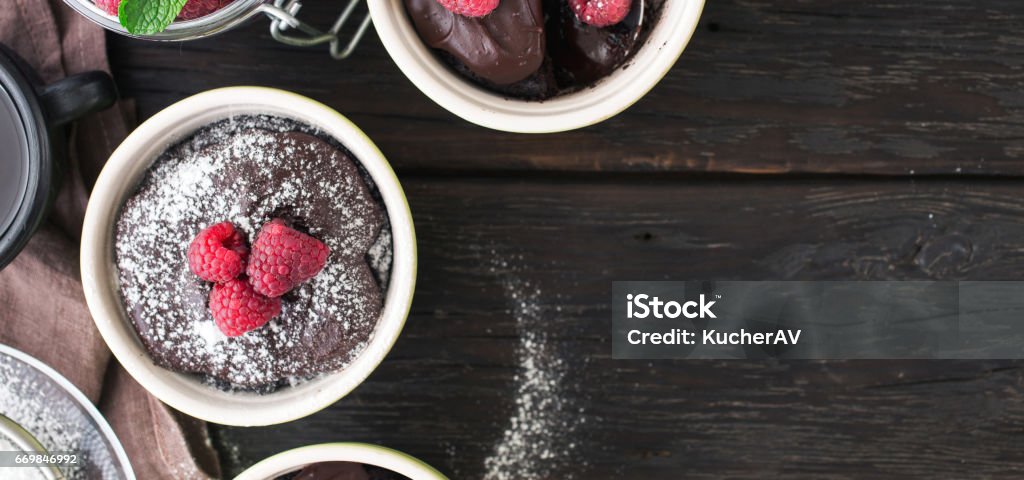 Chocolate cakes with berries on the dark wooden background with border Chocolate cakes with berries on the dark wooden background with border, top view Chocolate Stock Photo