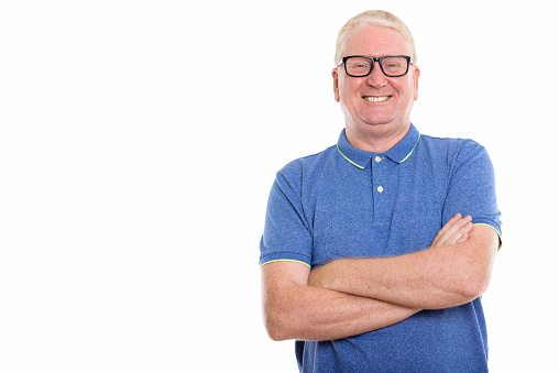 Studio shot of happy mature man smiling while wearing eyeglasses with arms crossed horizontal shot