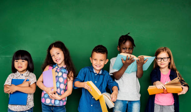 grupa dzieci w wieku szkolnym czytana dla edukacji - kid reading zdjęcia i obrazy z banku zdjęć