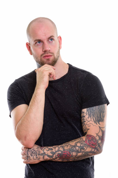 istock Studio shot of young bald muscular man with tattoos thinking while looking up 669859006
