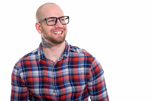 Close up of young happy bald muscular man smiling and wearing eyeglasses while thinking horizontal shot