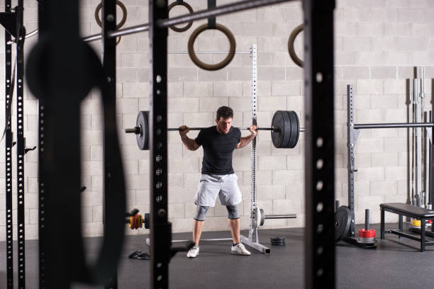 istock Man lifting heavy barbell on squat rack 669876042