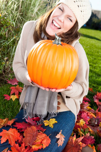 istock Smiling woman holding pumpkin 669877762