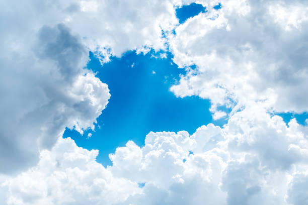 Looking up at Big white cloud and light ray behind cloud with blue sky.