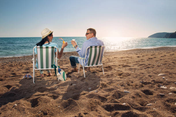 istock Rear view of couple in deck chairs on beach 669884366