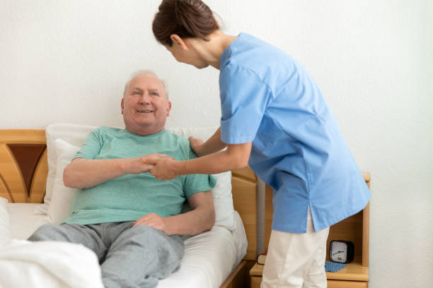 istock Female caregiver helping senior man 669885104